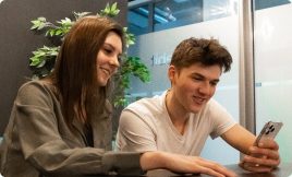 Two colleagues looking at a phone together in the office